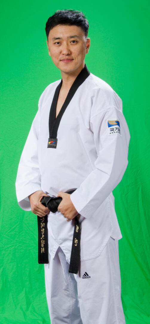 Master Jung standing upright, adjusting his belt