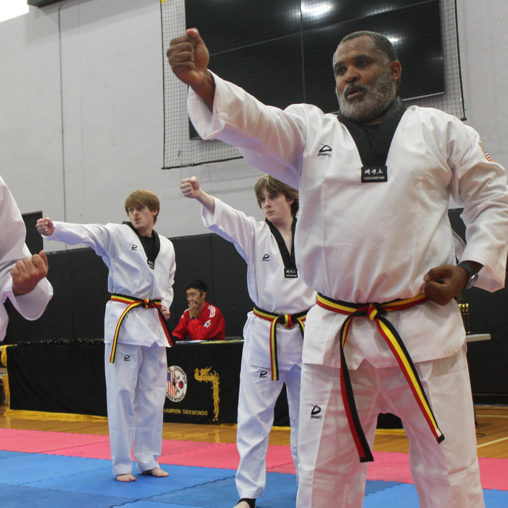 Three adult and teenage students are each demonstrating a close-handed strike