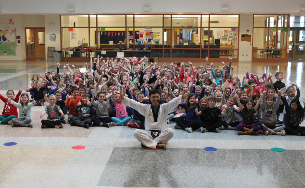 Master Jung and a large group of children at a public library smiling for a picture after completing a class